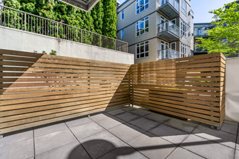 A wooden fence divides a concrete walkway.
